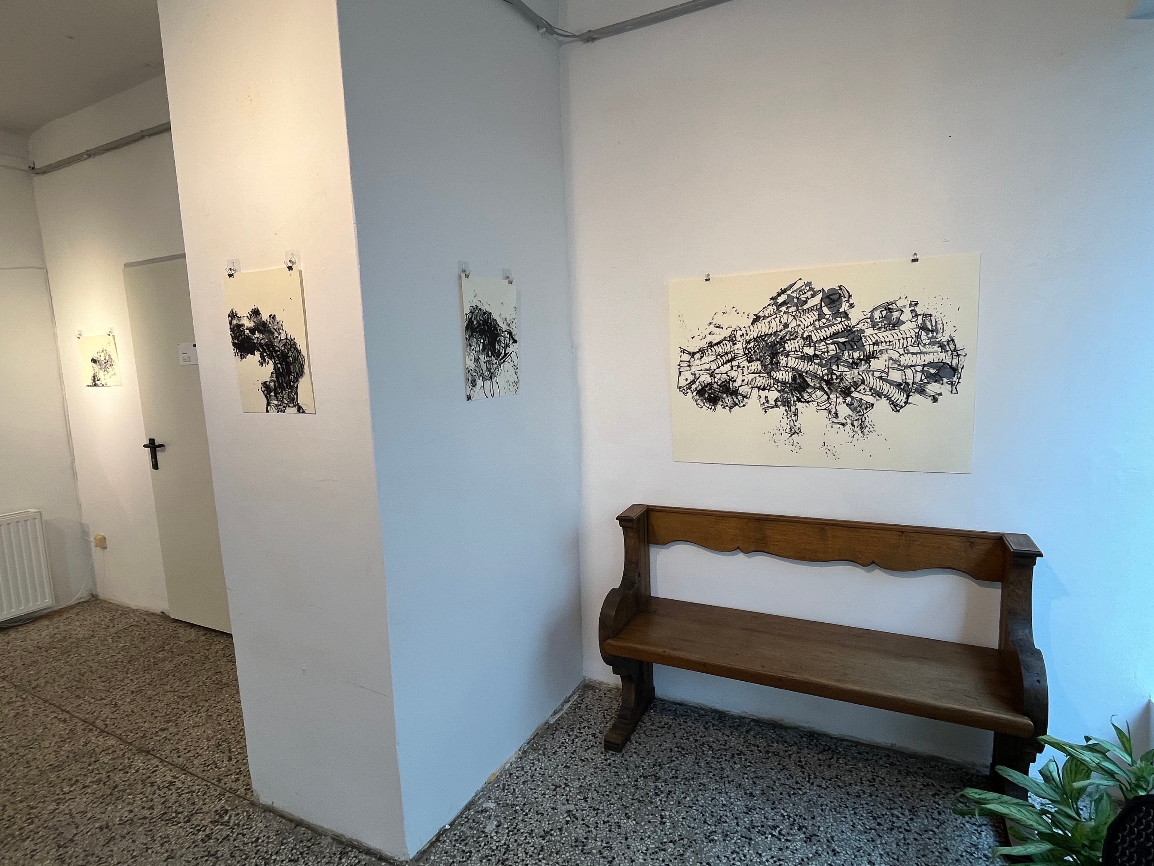 Gallery with black and white abstract paintings and a church bench